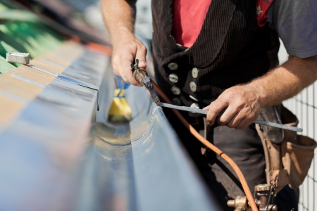 close-up of a roofer applying weld into the gutter parts to assemble it